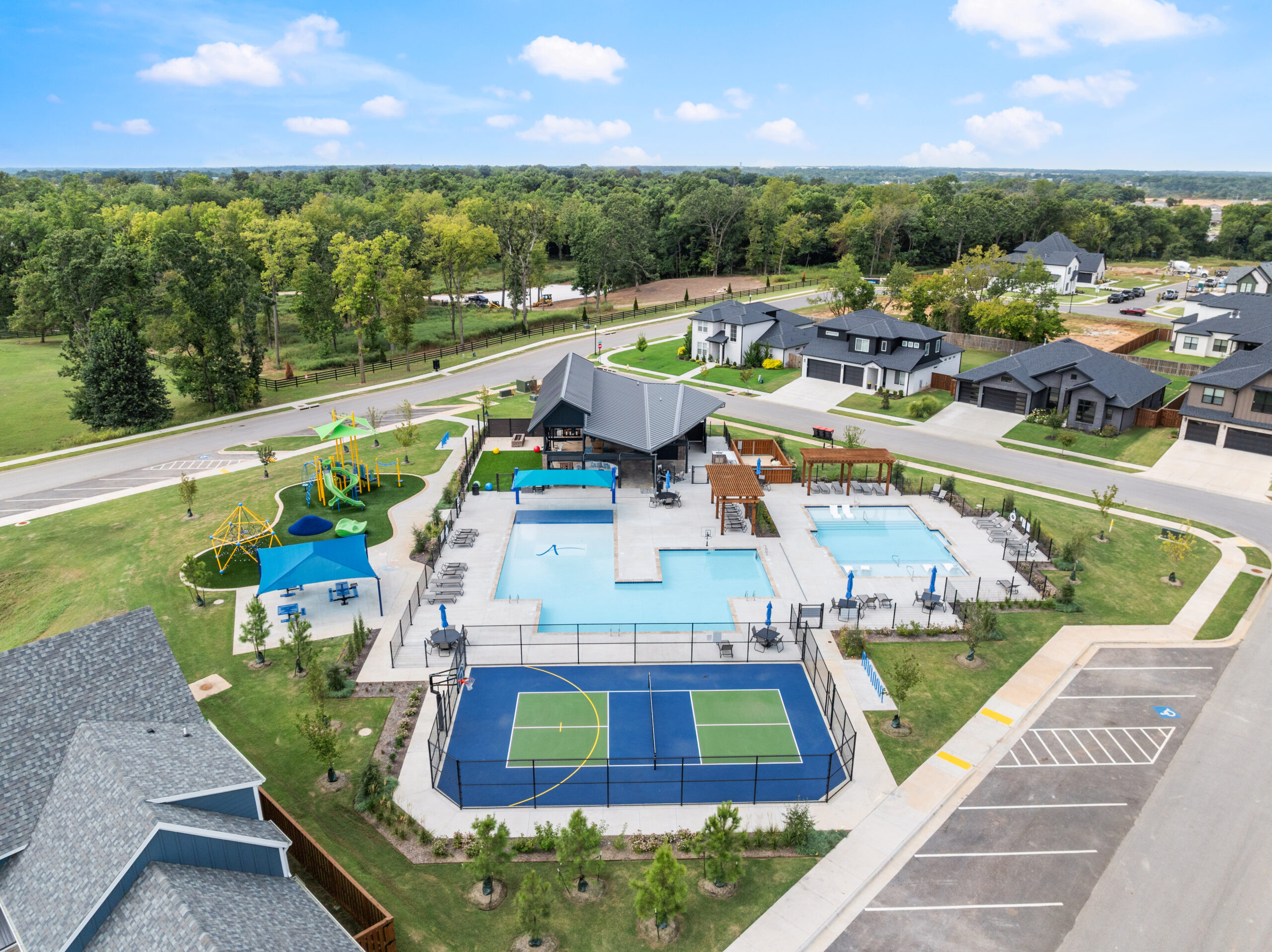 Aerial view of neighborhood amenities with pool, playground, sports court, and clubhouse.